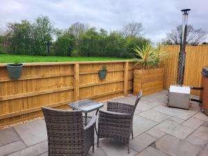 a patio with a table and chairs and a fence at The Old Barn in Hanbury
