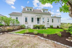 a white house with a stone wall at Marshside Cape Escape with Space Views in Sandwich