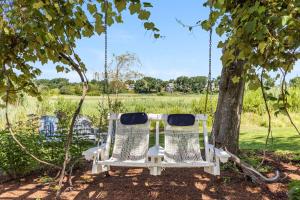 two chairs on a swing under a tree at Marshside Cape Escape with Space Views in Sandwich +53 photos