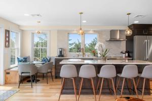 a kitchen with white chairs and a large kitchen island at Slow M'Ocean – A Fresh Take on Cape Calm in Chatham