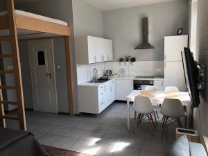 a kitchen with white cabinets and a table and chairs at Apartamenty Przy Plaży in Sopot