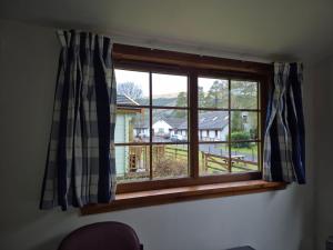a window with checkered curtains in a room at By The Way Campsite, Trekker, Nevis in Tyndrum