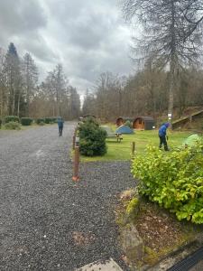 a group of people walking around a park with tents at By The Way Campsite, Trekker, Nevis in Tyndrum