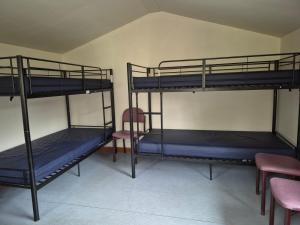 three bunk beds in a room with a table and chairs at By The Way Campsite, Trekker, Nevis in Tyndrum