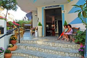 リミニにあるHotel Acquazzurraの二人の女性が店の外のベンチに座っている