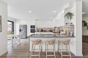 a kitchen with white cabinets and bar stools at Apartamento Cabine by Algarve Holidays in Quarteira
