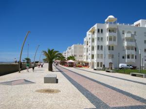 a street with a building and a palm tree in front at Apartamento Cabine by Algarve Holidays in Quarteira