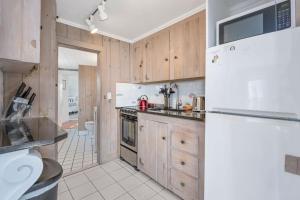 a kitchen with wooden cabinets and a white refrigerator at The Shell Cottage - Where Beach Dreams Begin in South Yarmouth +28 photos