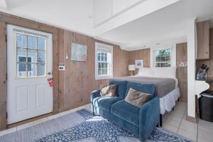 a bedroom with a bed and a blue chair at The Shell Cottage - Where Beach Dreams Begin in South Yarmouth