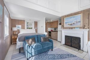 a bedroom with a bed and a chair and a fireplace at The Shell Cottage - Where Beach Dreams Begin in South Yarmouth