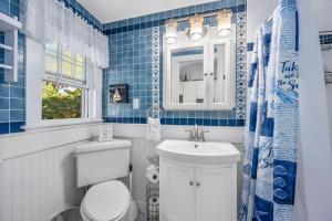 a blue tiled bathroom with a toilet and a sink at Lost at Seaside – Your Cozy Coastal Hideaway in South Yarmouth +28 photos