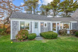 a white house with a yard with bushes at Oceans Edge: Drift, Dream, Repeat in South Yarmouth
