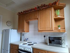 a kitchen with wooden cabinets and a white refrigerator at Pulteney Road Apartment in Bath