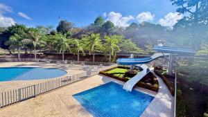 a swimming pool with a slide next to two pools at Citadela Di Sole Tropical Escape in Santa Fe de Antioquia