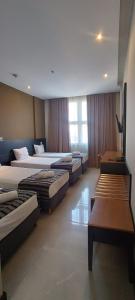 a hotel room with four beds and tables and a window at Hotel Atlântico Tower in Rio de Janeiro +66 photos