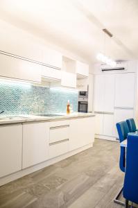 a kitchen with white cabinets and blue chairs at Blue Luxury Apartment in Budapest