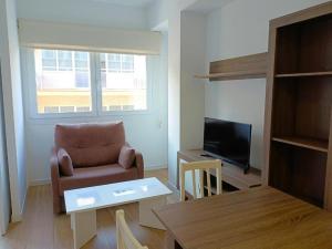 a living room with a chair and a television at Iberflat Apartamentos Marynton in Benicarló