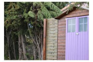 a garage with a purple door and some trees at La caravane plage in Pietroso