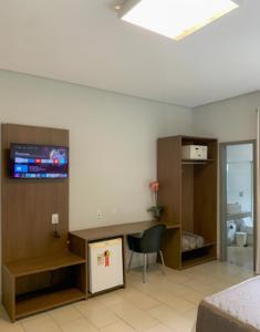 a room with a bed and a tv on a wall at Oásis Hotel in Araguaína