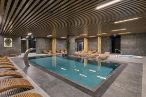 a pool in a hotel with chairs and a swimming pool at BANIA BLACK MOUNTAIN I basen & spa in Białka Tatrzańska