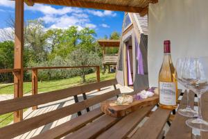 a bottle of wine on a wooden table with a glass at Glamping Le Ginestre in Monteverdi Marittimo