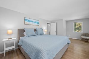 a white bedroom with a large bed with blue sheets at On Cape Time – Family Friendly Relaxing Escape in Osterville