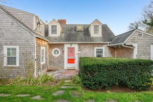 a house with a red door and a hedge at Peaceful Waterfront Cottage Escape in Eastham