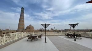 a patio with tables and chairs on a bridge with a tower at Sahro Hotel Khiva in Khiva