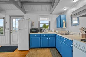 a kitchen with blue cabinets and a white refrigerator at Charming Waterfront Escape Along the Cove in Eastham