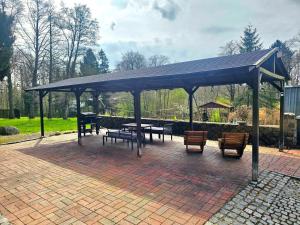 a pavilion with picnic tables and benches on a brick patio at Selker Noor Apartments - 1,4 ha Naturpark, privater Terrasse, Bachlauf an der Selker Wassermühle in Schleswig