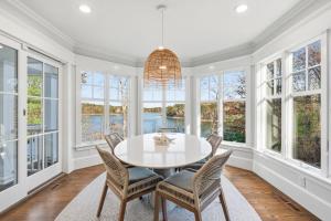 a dining room with a table and chairs and windows at Peaceful Cape Cod Escape with Pond Views Hot Tub in Sandwich