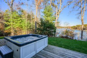 a hot tub on a deck with a view of the water at Peaceful Cape Cod Escape with Pond Views Hot Tub in Sandwich