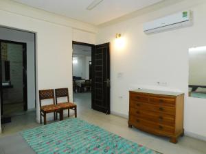 a bedroom with a dresser and a bed and a chair at Home By The Park in New Delhi