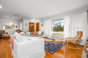 a living room with white furniture and a large window at Relaxing Barnstable Getaway Close to the Beach in Barnstable
