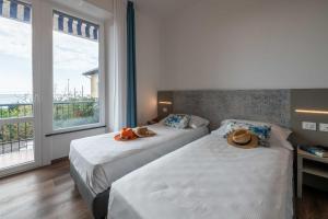 zwei Betten in einem Hotelzimmer mit zwei Hüten darauf in der Unterkunft Real Park Hotel in Cavi di Lavagna