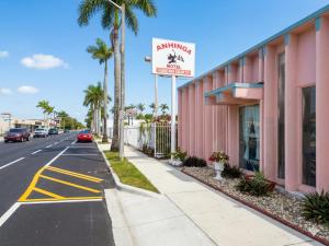 a street in front of a pink building with a parking sign at Anhinga Motel Homestead FL in Homestead