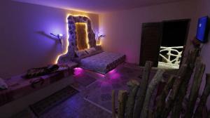 a room with purple lighting and a bed and chairs at Résidence Arinas in Al Barāwikah