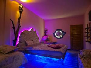 a bedroom with a bed with purple lights on it at Résidence Arinas in Al Barāwikah
