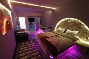 a bedroom with a large bed with purple lights at Résidence Arinas in Al Barāwikah