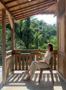 a woman sitting on a wooden bench on a porch at Verdana Jungle Retreat Ubud in Ubud