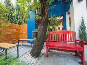 a red bench sitting next to a tree at Shade House - Bitec Bangna in Bangkok