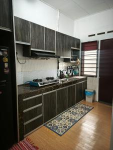 a kitchen with wooden cabinets and a rug on the floor at Homestay Idora PD in Port Dickson