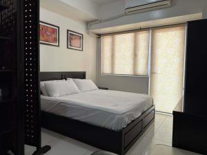 a bedroom with a bed and two windows at SMDC Tagaytay Condominium in Kaybagal