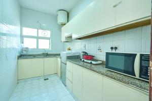 a white kitchen with a microwave and a sink at Quality Hotel Apartments in Sabkhah