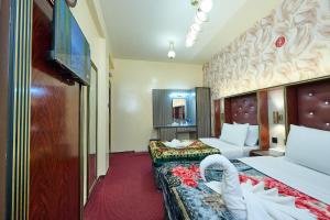 a hotel room with two beds and a flat screen tv at Quality Hotel Apartments in Sabkhah