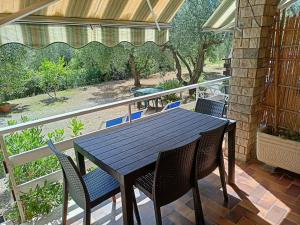 a table and chairs on a porch with a view of a garden at L'oleandra appartamenti in Lacona
