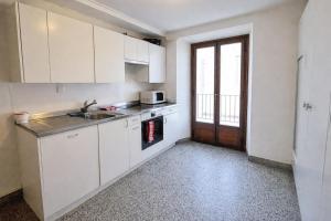 a kitchen with white cabinets and a sink and a window at Casa Arcobaleno in Airolo