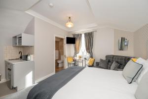 a bedroom with a large white bed and a kitchen at Abbey View Townhouse in Youghal