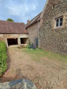 a brick building with a bench in the yard at Gîte Léon - Au cœur du village 4 pers in Gargilesse-Dampierre