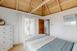 a white bedroom with a bed and a window at La Casa De La Playa in Gloucester